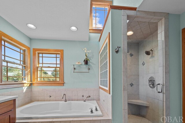 bathroom with a stall shower, recessed lighting, a bath, and vanity