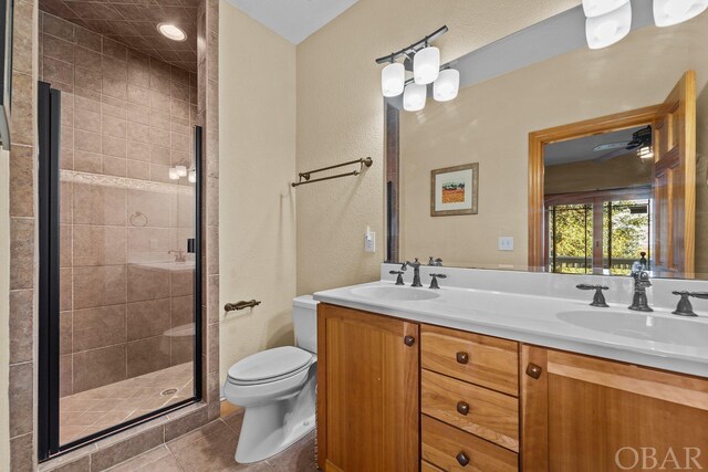 full bathroom with double vanity, a stall shower, toilet, and a sink