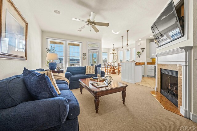 living room featuring ceiling fan, a fireplace with flush hearth, and light colored carpet