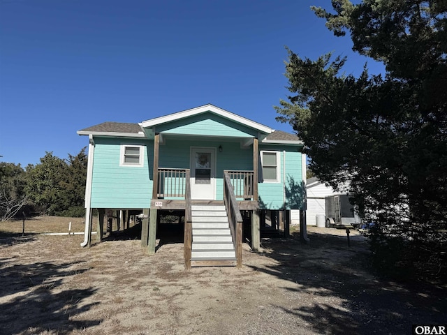 view of front of house featuring a porch, a shingled roof, driveway, stairway, and a carport