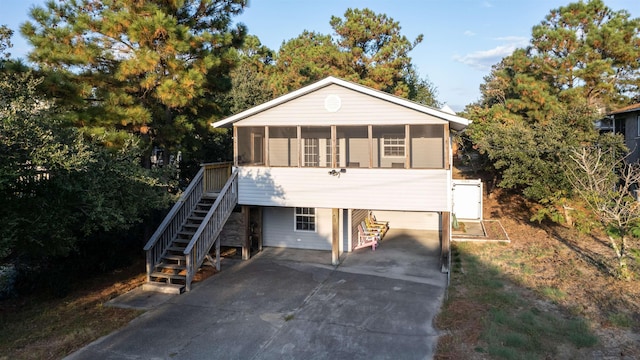 view of front of house featuring driveway, a sunroom, stairs, and a carport