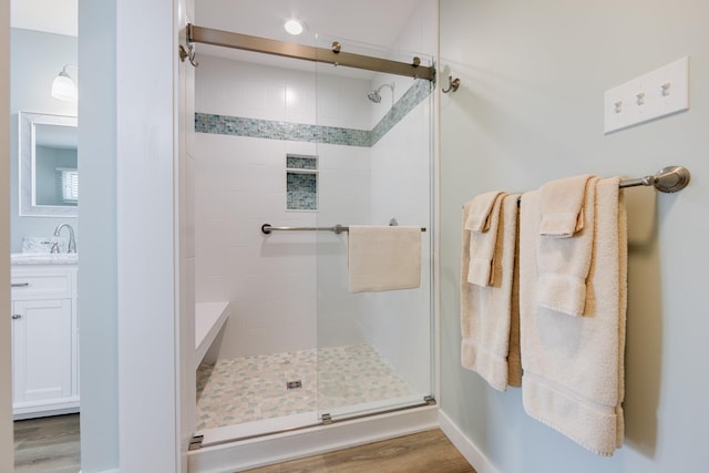 full bathroom with wood finished floors, a shower stall, and vanity