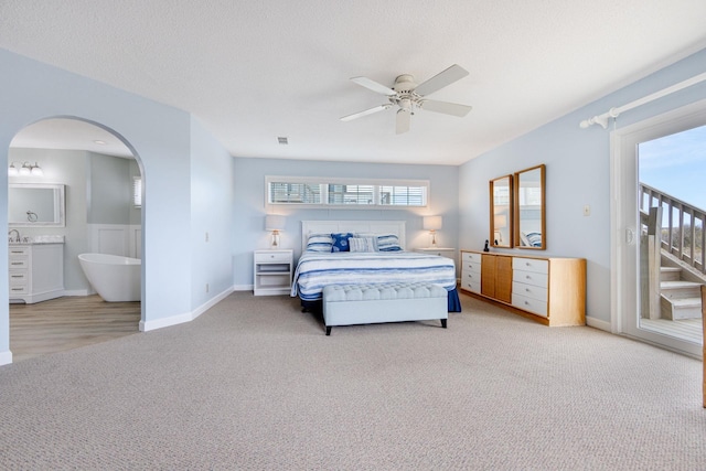 bedroom with arched walkways, light colored carpet, ceiling fan, access to exterior, and a textured ceiling