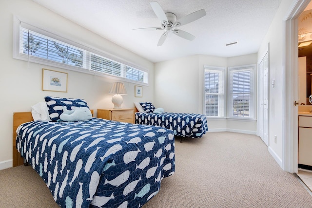 bedroom with visible vents, baseboards, a textured ceiling, and light colored carpet