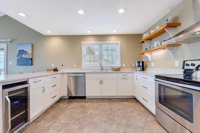 kitchen with beverage cooler, a peninsula, stainless steel appliances, light countertops, and white cabinetry