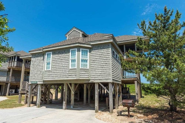 view of side of home with a carport, concrete driveway, and a balcony