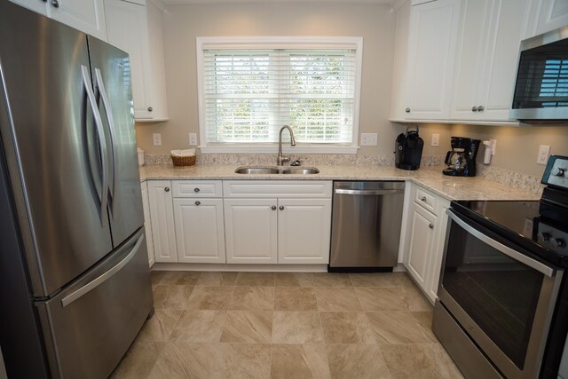 kitchen featuring stainless steel appliances, white cabinetry, a sink, and light stone counters