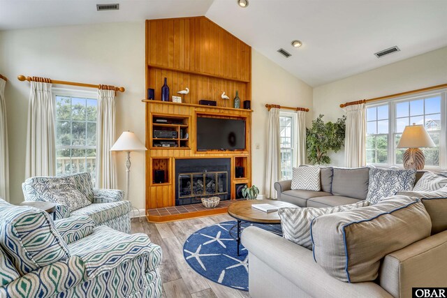 living area with high vaulted ceiling, wood finished floors, and visible vents