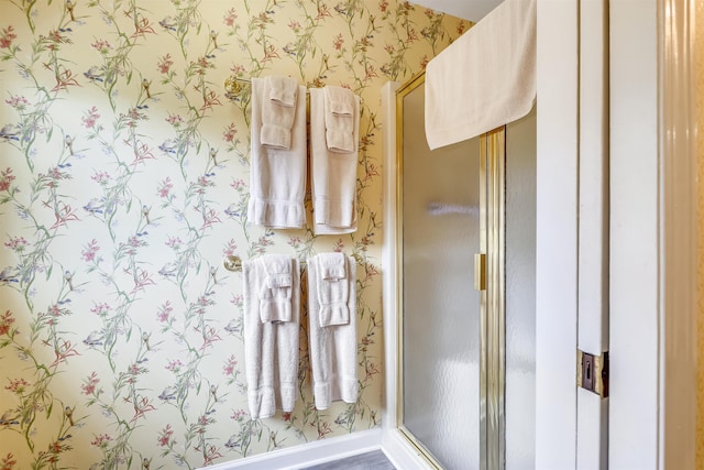 bathroom featuring baseboards, a shower stall, and wallpapered walls