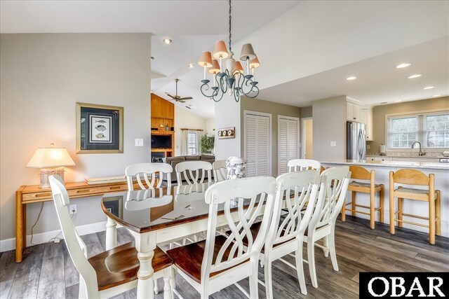 dining area with lofted ceiling, recessed lighting, an inviting chandelier, dark wood-type flooring, and baseboards