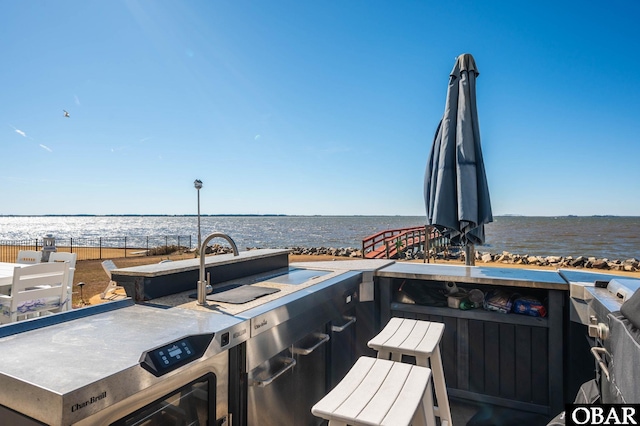 view of patio featuring a water view and fence