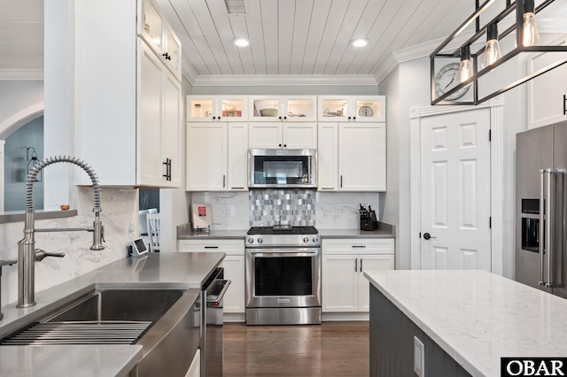 kitchen featuring white cabinets, glass insert cabinets, stainless steel appliances, and decorative light fixtures