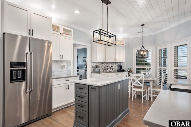 kitchen featuring high quality fridge, white cabinetry, hanging light fixtures, gray cabinets, and glass insert cabinets