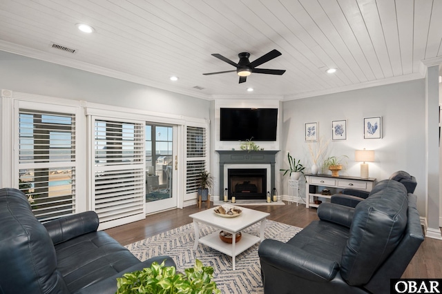 living area with a fireplace with raised hearth, recessed lighting, dark wood-style flooring, visible vents, and ornamental molding