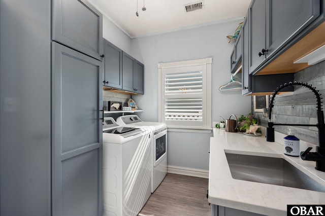 washroom with a sink, visible vents, cabinet space, dark wood-style floors, and washer and clothes dryer