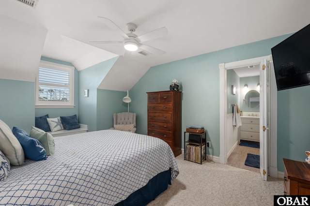 bedroom featuring light carpet, baseboards, visible vents, lofted ceiling, and ensuite bathroom