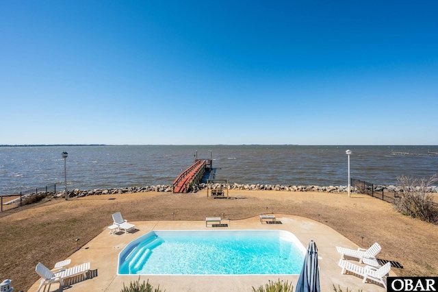 community pool with a water view, a patio area, and fence