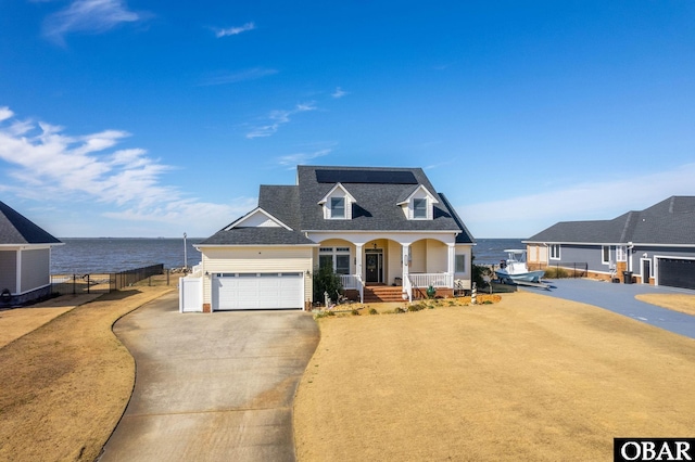 view of front of home featuring driveway, a garage, a water view, fence, and a porch