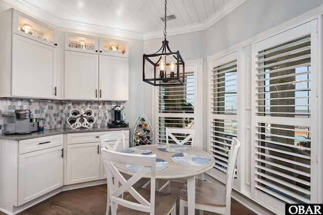 dining area with dark wood-style floors, a notable chandelier, visible vents, ornamental molding, and wooden ceiling