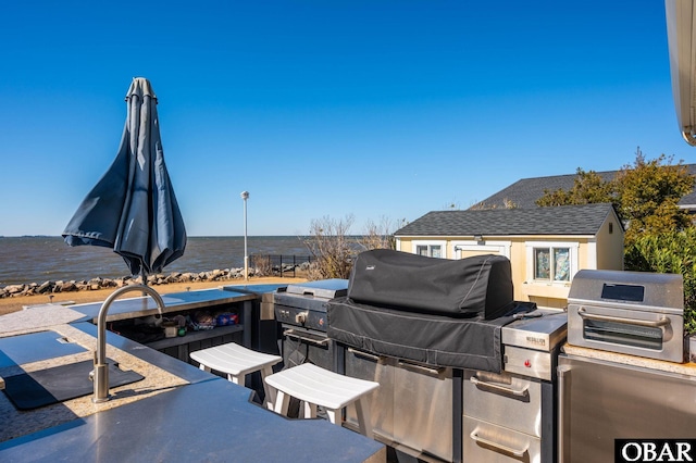 view of patio / terrace featuring area for grilling, an outdoor kitchen, and a water view