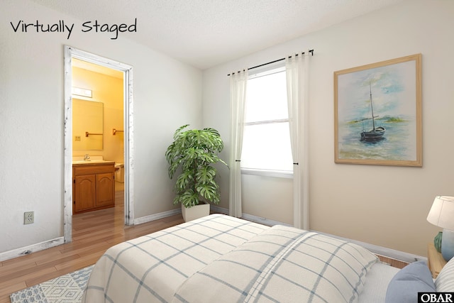 549 White Whale Way Lot # 220E, Corolla, NC 27927 - bedroom featuring wood finished floors, baseboards, a sink, ensuite bath, and a textured ceiling