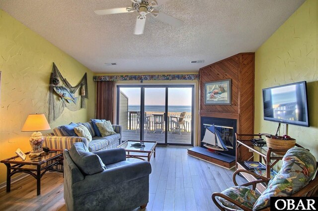 2035 S Virginia Dare Trl Unit 11, Kill Devil Hills, NC 27948 - living area with a textured ceiling, a textured wall, hardwood / wood-style floors, a ceiling fan, and a glass covered fireplace