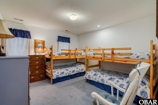 carpeted bedroom featuring visible vents and a textured ceiling