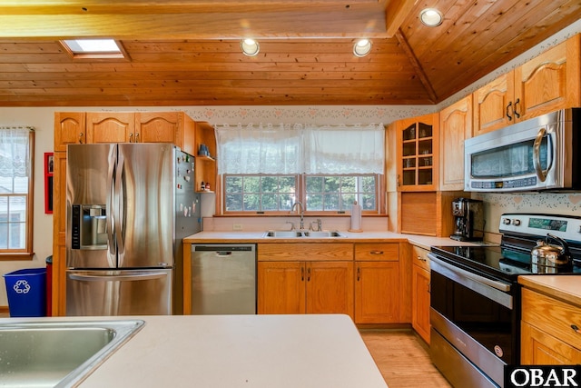 kitchen with a sink, vaulted ceiling, wood ceiling, and stainless steel appliances