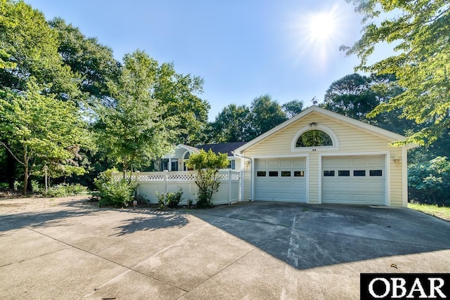 garage featuring driveway and fence