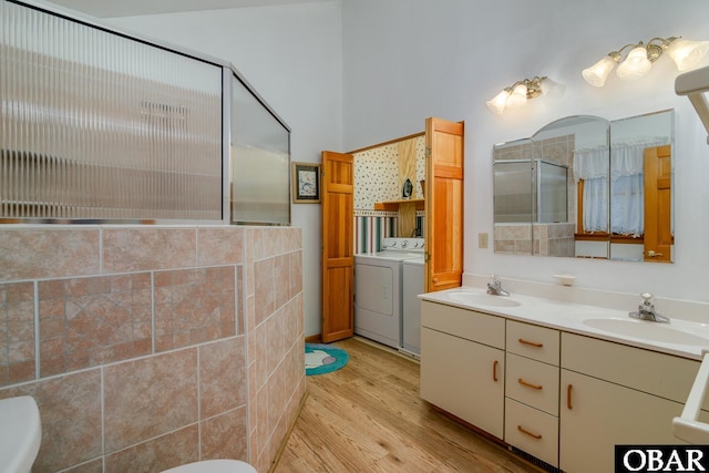 bathroom featuring independent washer and dryer, a stall shower, wood finished floors, and a sink