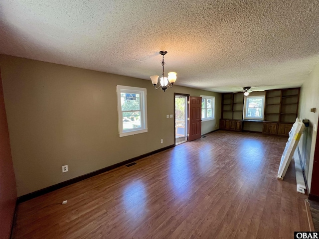 108 Loop Rd, Ocracoke, NC 27960 - empty room featuring a textured ceiling, dark wood finished floors, ceiling fan, a chandelier, and baseboards