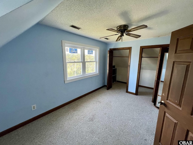 108 Loop Rd, Ocracoke, NC 27960 - unfurnished bedroom featuring multiple closets, light carpet, baseboards, a textured ceiling, and lofted ceiling