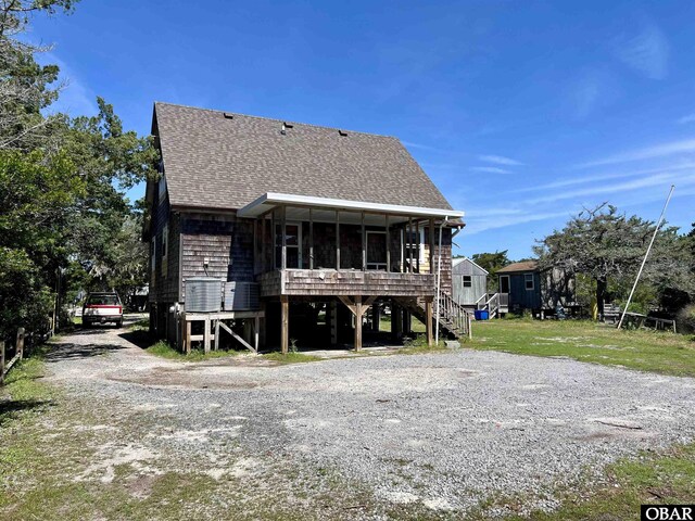 108 Loop Rd, Ocracoke, NC 27960 - back of property featuring a sunroom, roof with shingles, stairs, and driveway