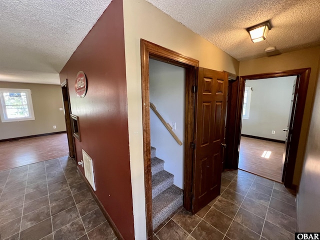108 Loop Rd, Ocracoke, NC 27960 - corridor featuring a textured ceiling, dark tile patterned floors, stairway, and baseboards