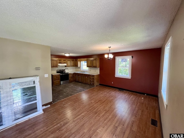 108 Loop Rd, Ocracoke, NC 27960 - kitchen featuring stainless steel range with electric cooktop, under cabinet range hood, a textured ceiling, a chandelier, and dark wood-style floors