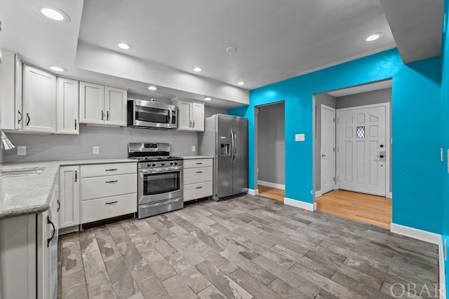 kitchen with baseboards, white cabinetry, stainless steel appliances, and recessed lighting