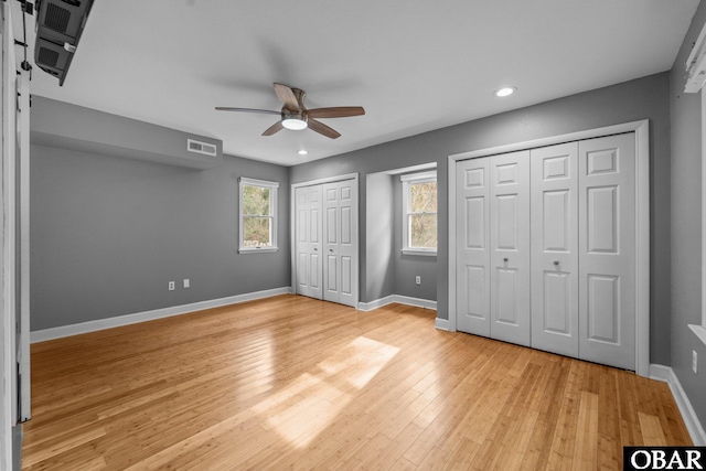 unfurnished bedroom featuring recessed lighting, visible vents, baseboards, multiple closets, and light wood-type flooring