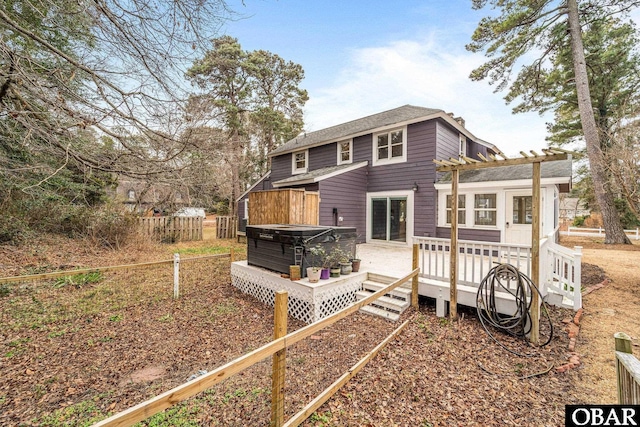 rear view of property with a deck, fence, and a hot tub