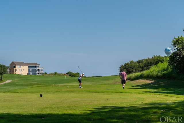 view of community featuring view of golf course and a lawn