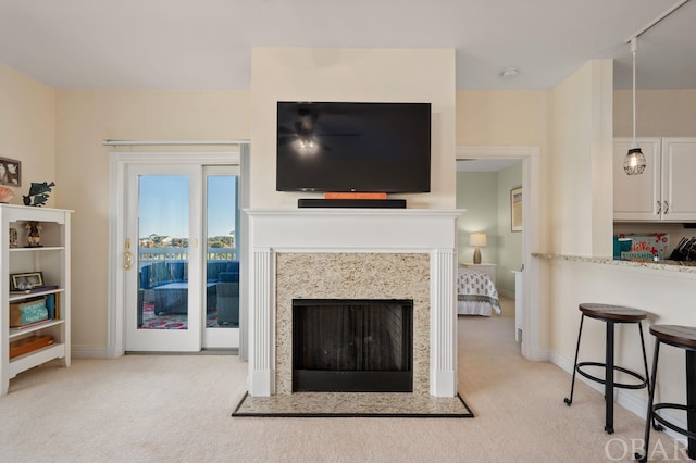 living area with light carpet, a fireplace with raised hearth, and baseboards