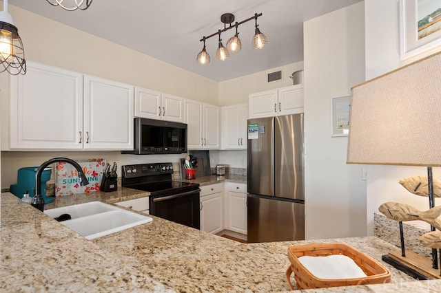 kitchen featuring light stone counters, stainless steel appliances, a sink, white cabinets, and hanging light fixtures