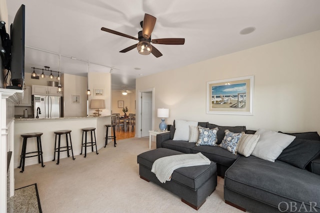 living room with ceiling fan, track lighting, and light colored carpet