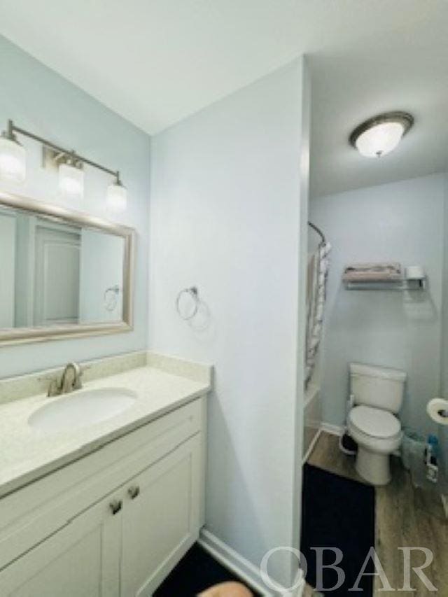 bathroom featuring toilet, baseboards, shower / bath combo with shower curtain, and vanity