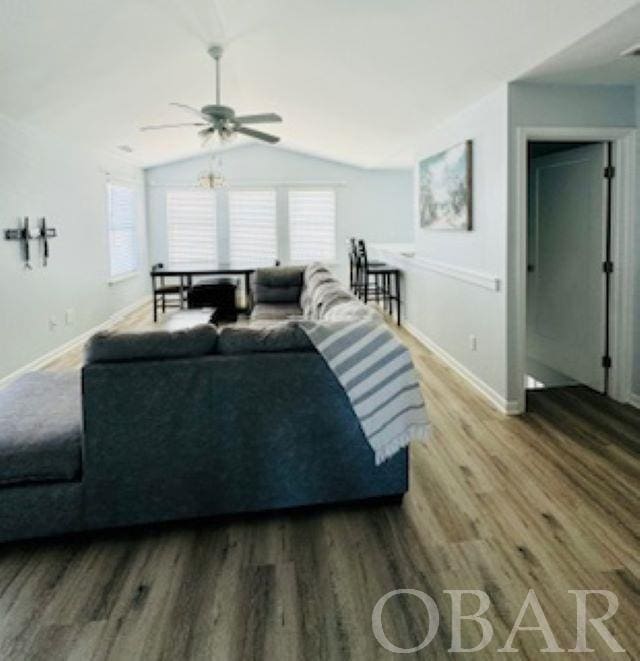 living room with lofted ceiling, wood finished floors, a ceiling fan, and baseboards