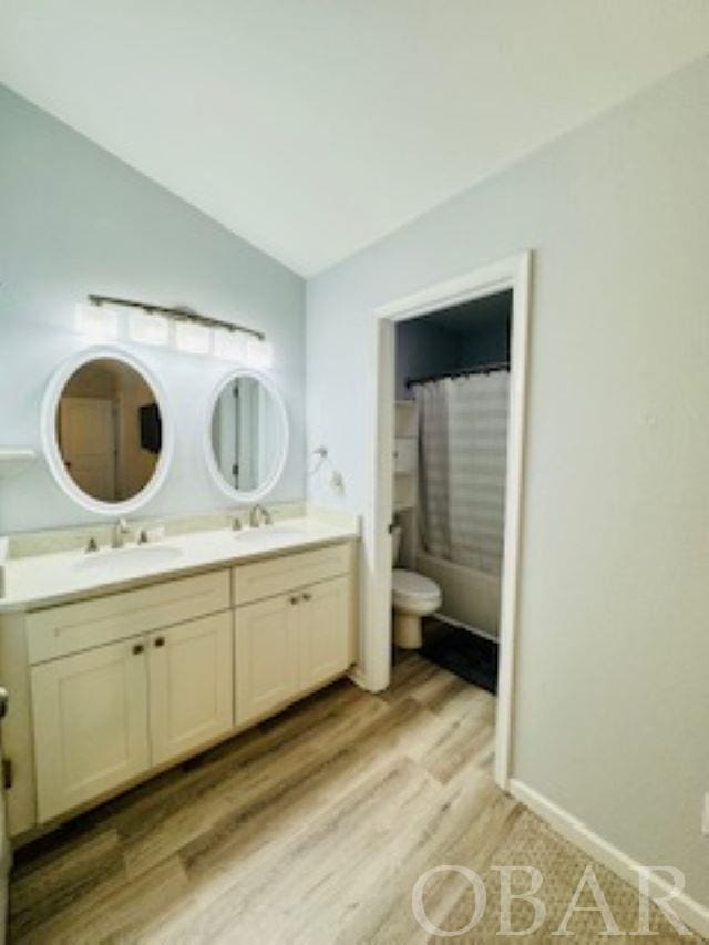 bathroom with double vanity, baseboards, a sink, and wood finished floors