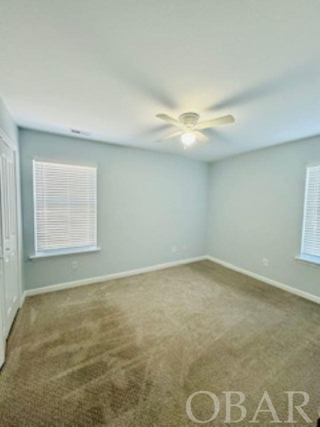 spare room featuring carpet flooring, a ceiling fan, and baseboards