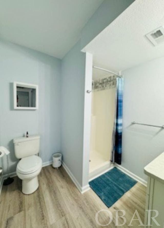 full bath with a stall shower, vanity, toilet, and wood finished floors