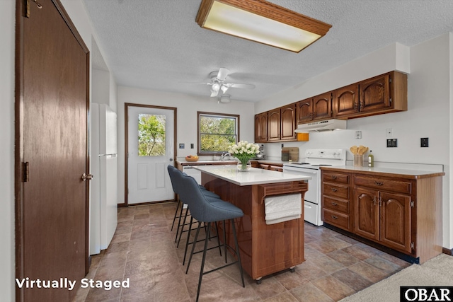 116 W Old Cove Rd Lot 1, Nags Head, NC 27959 - kitchen featuring a kitchen breakfast bar, a textured ceiling, white appliances, under cabinet range hood, and light countertops