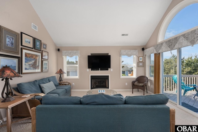 carpeted living area featuring high vaulted ceiling, a healthy amount of sunlight, visible vents, and a fireplace