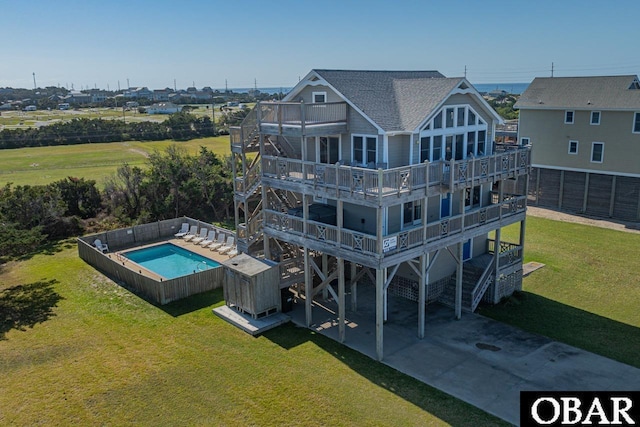 rear view of house featuring roof with shingles, a yard, concrete driveway, a balcony, and a carport